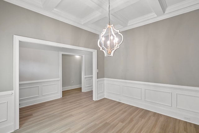 empty room featuring crown molding, light hardwood / wood-style flooring, an inviting chandelier, beam ceiling, and coffered ceiling