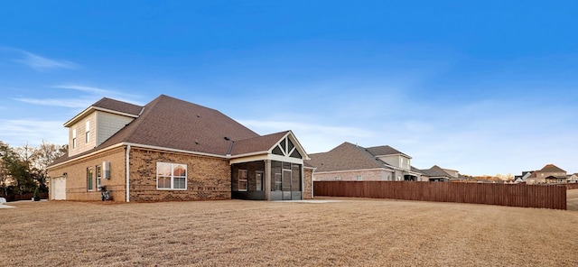 back of property featuring a sunroom and a lawn