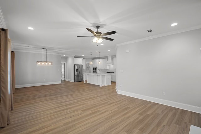 unfurnished living room featuring ornamental molding, sink, ceiling fan, and light hardwood / wood-style floors