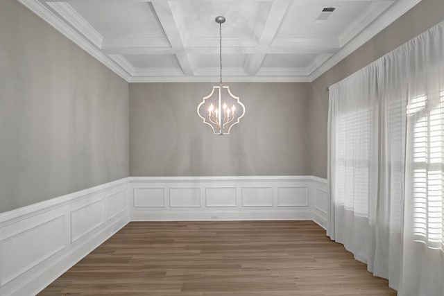 unfurnished dining area with beamed ceiling, coffered ceiling, hardwood / wood-style flooring, and a notable chandelier