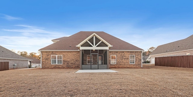 rear view of property featuring a patio, a yard, and a sunroom