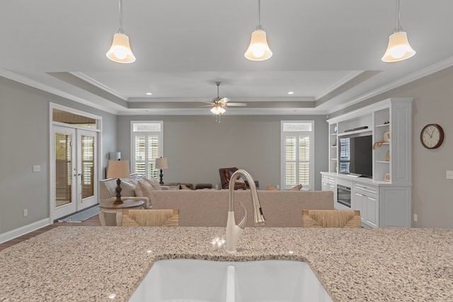 kitchen with a raised ceiling, french doors, pendant lighting, and sink