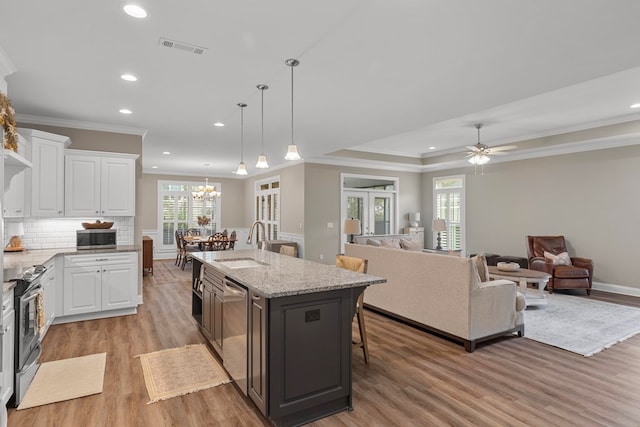 kitchen featuring sink, white cabinetry, decorative light fixtures, and a kitchen island with sink