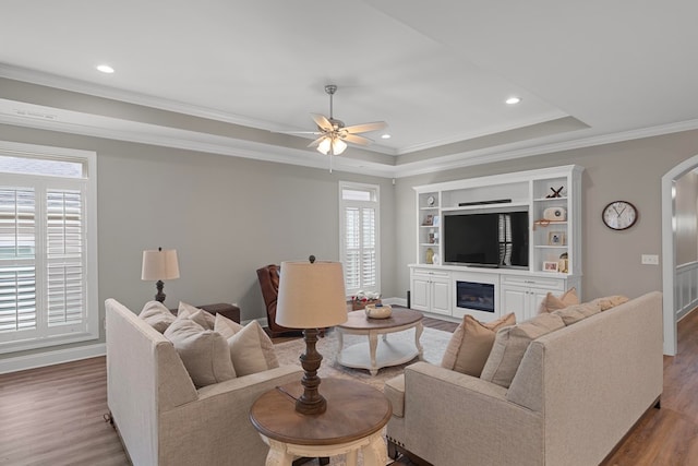 living room featuring ornamental molding, ceiling fan, a tray ceiling, and hardwood / wood-style floors