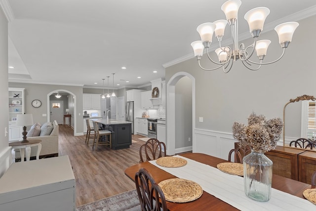 dining room with a notable chandelier, crown molding, and light hardwood / wood-style flooring