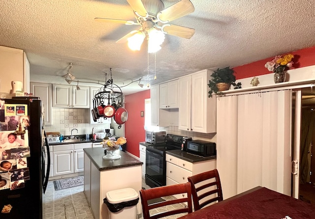 kitchen with a center island, white cabinetry, decorative backsplash, black appliances, and dark countertops