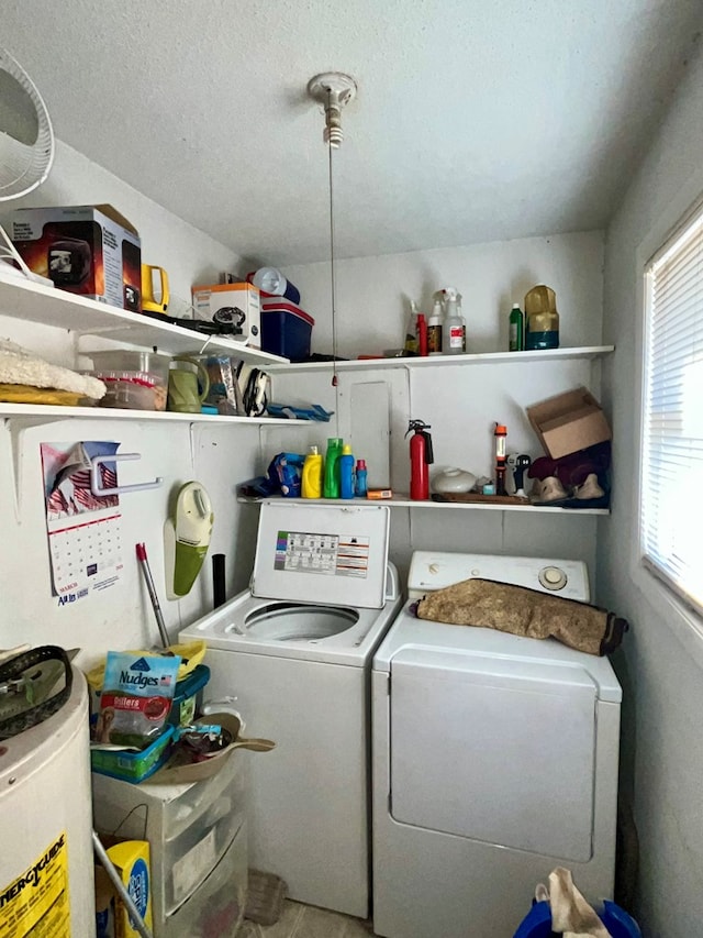 laundry room featuring washing machine and dryer, laundry area, water heater, and a textured ceiling