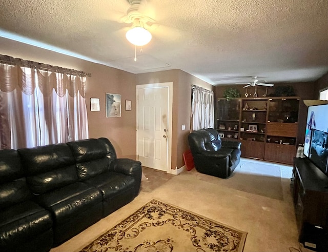 living area with a textured ceiling, carpet floors, and a ceiling fan