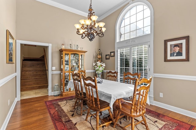 dining area featuring crown molding, hardwood / wood-style floors, a high ceiling, and a notable chandelier