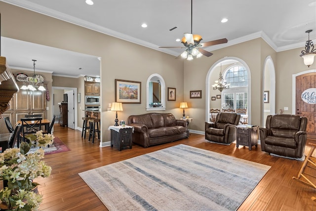 living room featuring dark wood-type flooring, ceiling fan with notable chandelier, and ornamental molding