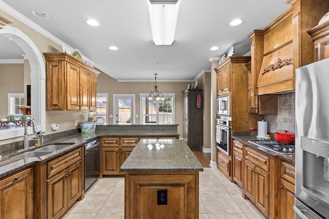 kitchen with tasteful backsplash, stainless steel appliances, crown molding, sink, and a center island