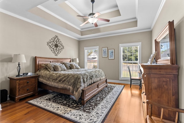 bedroom featuring a raised ceiling, ceiling fan, wood-type flooring, and ornamental molding