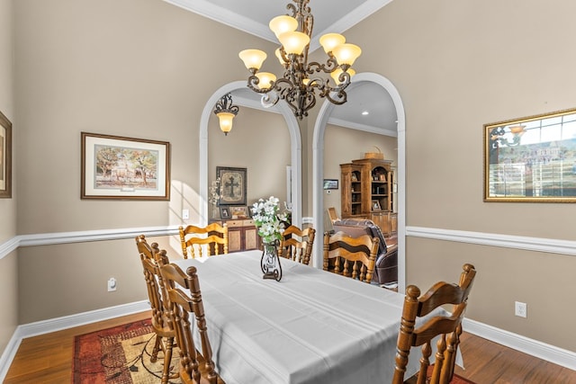 dining area featuring crown molding, hardwood / wood-style floors, and a notable chandelier