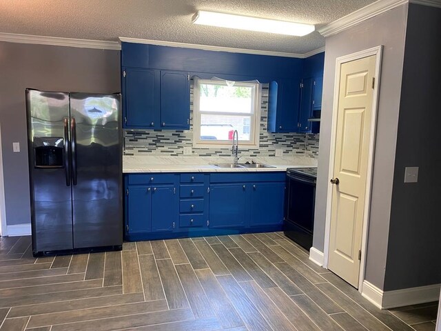 kitchen with sink, dark wood-type flooring, black range with electric cooktop, blue cabinets, and stainless steel fridge