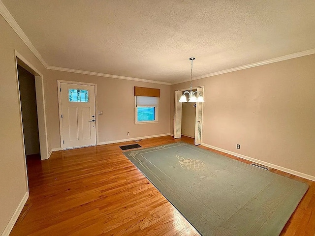 foyer entrance featuring hardwood / wood-style floors, a chandelier, a textured ceiling, and ornamental molding