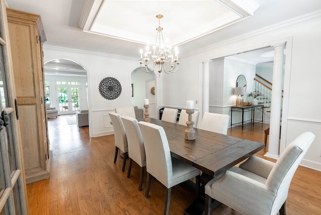 dining room featuring light hardwood / wood-style floors, crown molding, a tray ceiling, and a chandelier