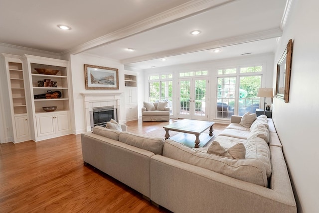 living room featuring a fireplace, hardwood / wood-style floors, built in features, and crown molding