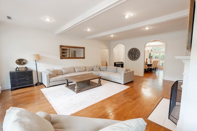 living room featuring beamed ceiling, light hardwood / wood-style floors, and ornamental molding