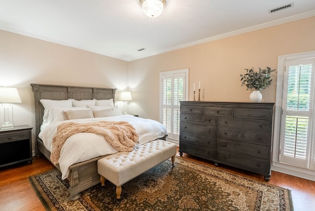 bedroom featuring multiple windows, wood-type flooring, and ornamental molding