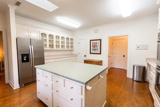 kitchen featuring stainless steel fridge with ice dispenser, a center island, white cabinetry, and ornamental molding