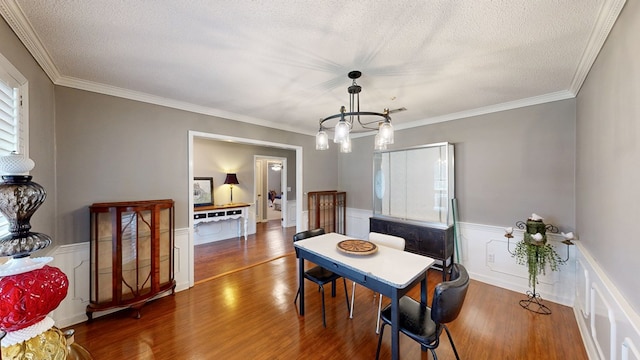 103 Yorkshire St, Dothan, AL 36305 - dining area with wood finished floors, a wainscoted wall, a textured ceiling, a chandelier, and crown molding