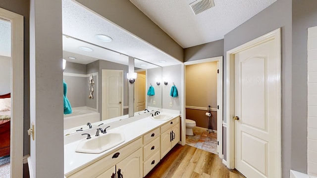 103 Yorkshire St, Dothan, AL 36305 - full bathroom with double vanity, wood finished floors, a tub, and a textured ceiling
