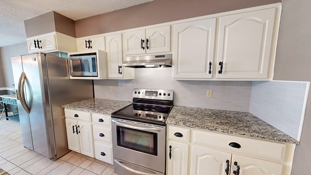 103 Yorkshire St, Dothan, AL 36305 - kitchen with appliances with stainless steel finishes, under cabinet range hood, a textured ceiling, backsplash, and light stone counters