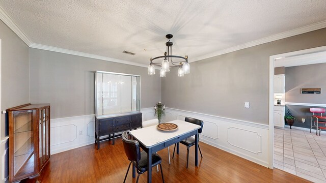 103 Yorkshire St, Dothan, AL 36305 - dining room featuring a textured ceiling, wood finished floors, a chandelier, ornamental molding, and a wainscoted wall