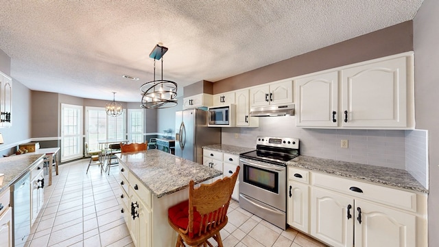 103 Yorkshire St, Dothan, AL 36305 - kitchen featuring appliances with stainless steel finishes, under cabinet range hood, a chandelier, light tile patterned floors, and backsplash