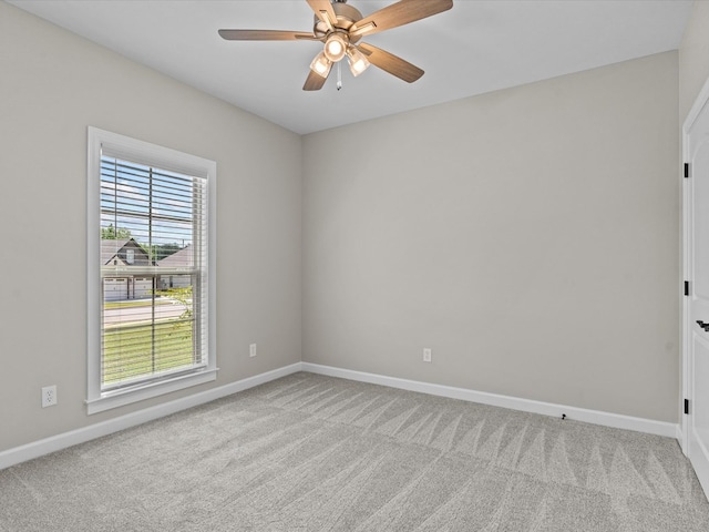 carpeted empty room featuring baseboards and a ceiling fan
