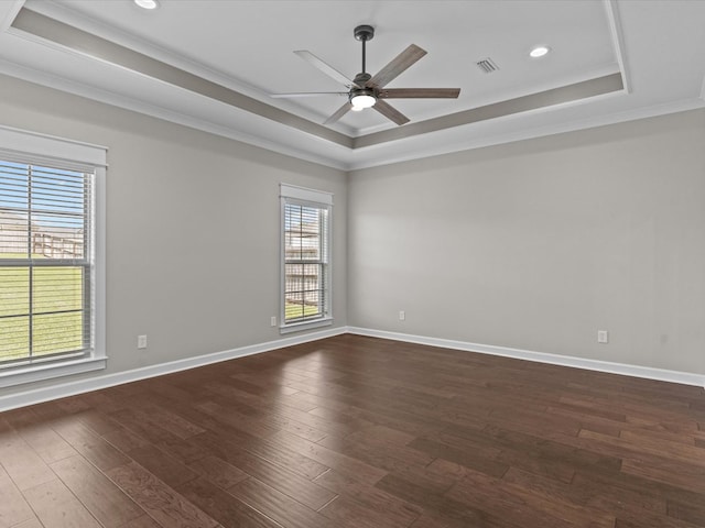 empty room featuring a raised ceiling, ceiling fan, crown molding, dark wood-style floors, and recessed lighting