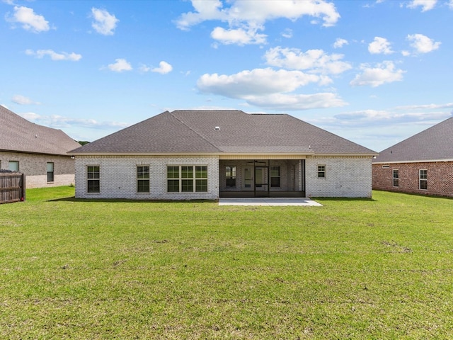 back of house with a yard, a sunroom, brick siding, and a patio area