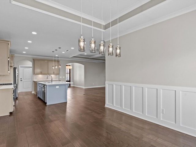 kitchen featuring arched walkways, open floor plan, a sink, light countertops, and crown molding