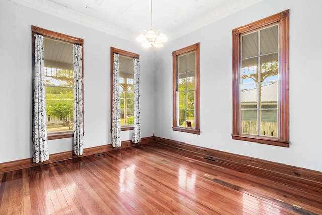 spare room with crown molding, hardwood / wood-style floors, and a chandelier