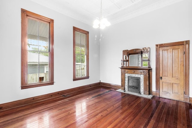 unfurnished living room with hardwood / wood-style floors, an inviting chandelier, ornamental molding, and a premium fireplace