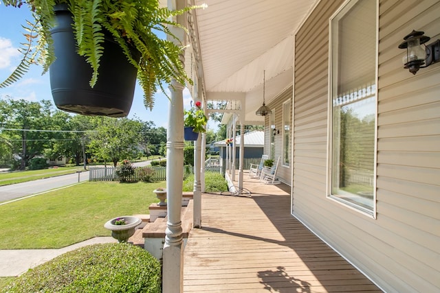 wooden terrace featuring a porch and a yard