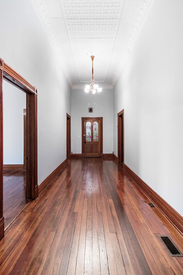 foyer with ornamental molding, a high ceiling, dark hardwood / wood-style floors, and an inviting chandelier