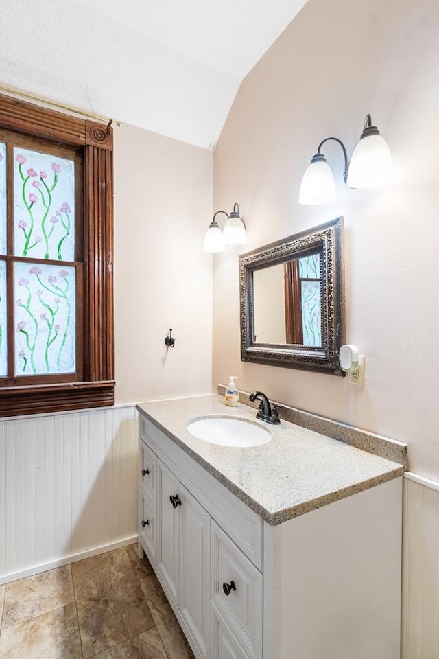 bathroom featuring vanity, a healthy amount of sunlight, and vaulted ceiling