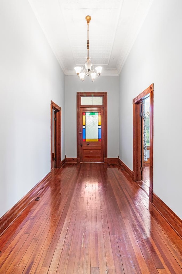 entrance foyer featuring dark hardwood / wood-style flooring, ornamental molding, and a notable chandelier