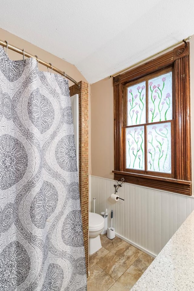 bathroom featuring a textured ceiling, toilet, and lofted ceiling