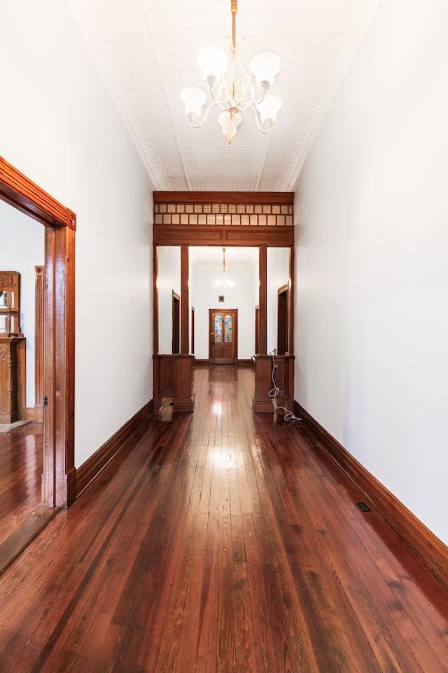 hallway with dark hardwood / wood-style floors and an inviting chandelier