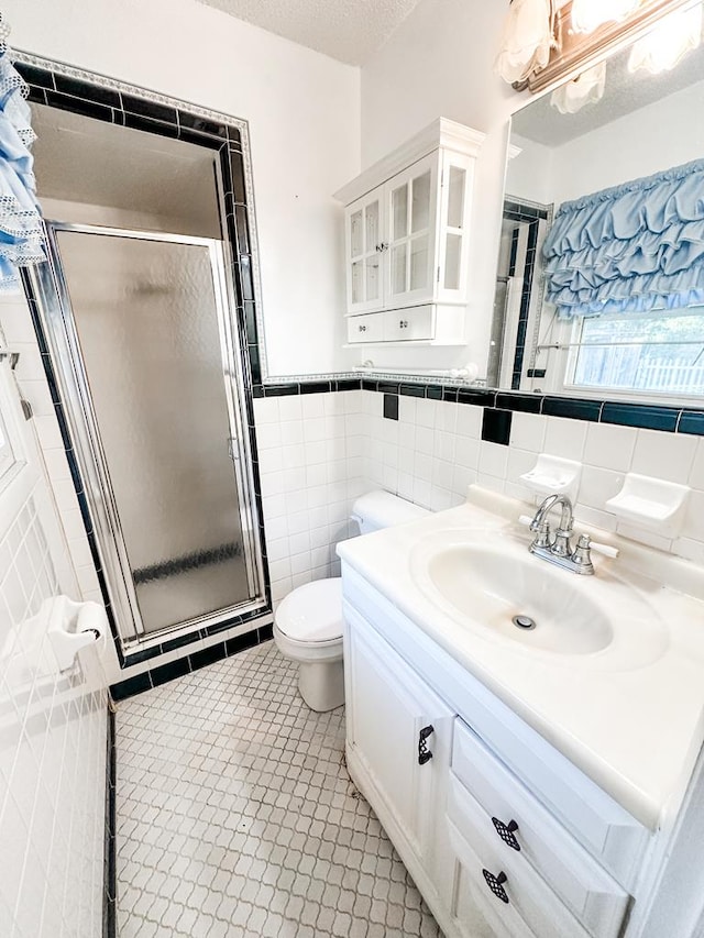 bathroom featuring walk in shower, vanity, tile walls, tile patterned flooring, and toilet