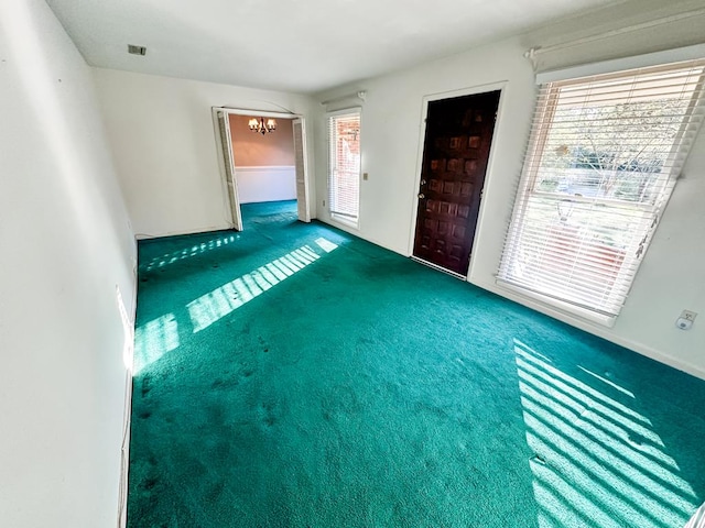 unfurnished living room featuring carpet flooring and a notable chandelier