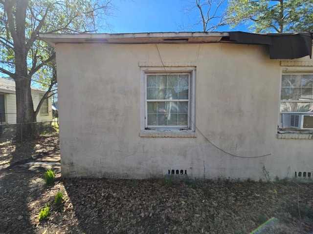 view of side of home featuring cooling unit, crawl space, fence, and stucco siding