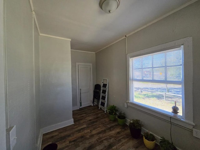 empty room with ornamental molding, dark wood finished floors, and baseboards