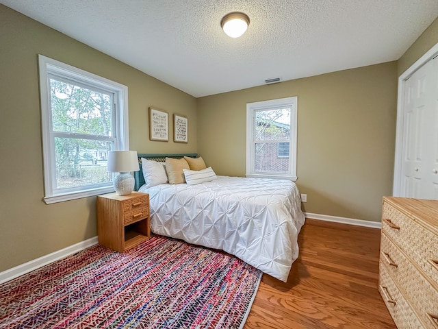 bedroom featuring wood-type flooring, a textured ceiling, and a closet