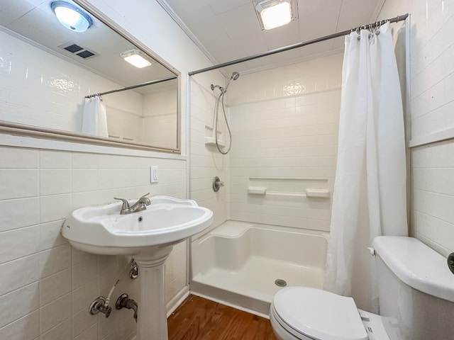 bathroom featuring a shower with shower curtain, crown molding, hardwood / wood-style flooring, tile walls, and toilet