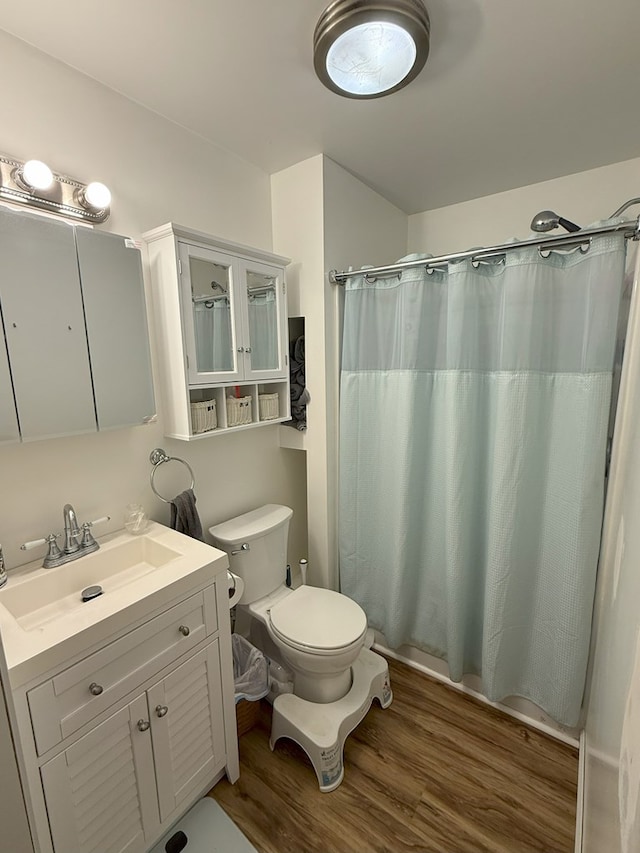 bathroom with hardwood / wood-style flooring, vanity, a shower with shower curtain, and toilet