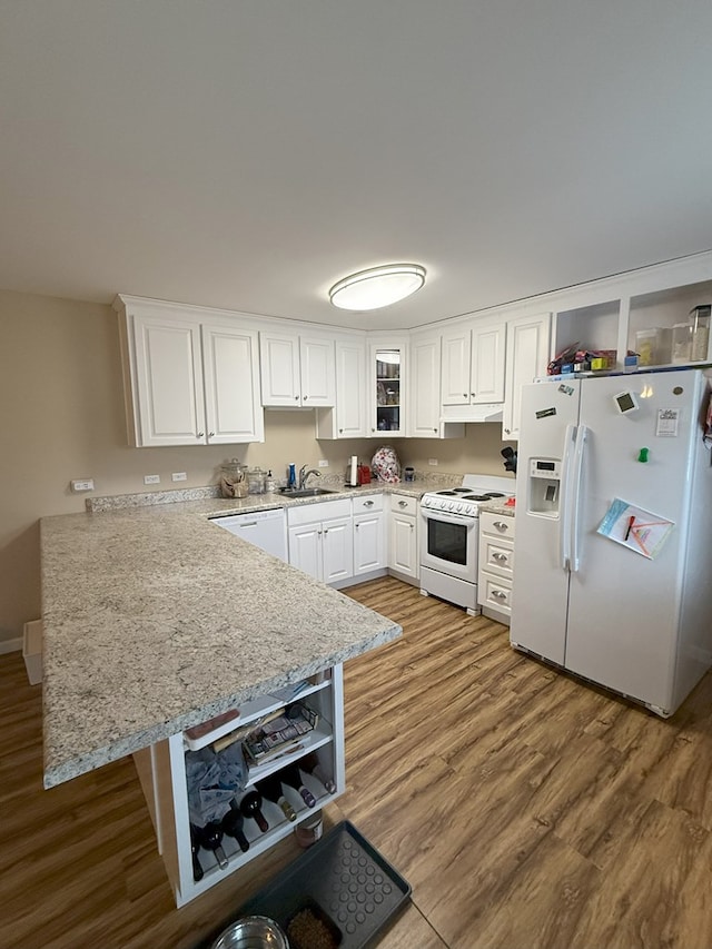 kitchen with sink, white appliances, kitchen peninsula, and white cabinets