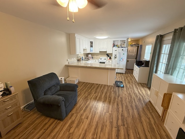 kitchen with white appliances, hardwood / wood-style floors, light stone countertops, white cabinets, and kitchen peninsula